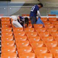 Taking out the trash: Japanese soccer fans collect trash at the end of the match between Japan and Senegal at the 2018 World Cup in Yekaterinburg, Russia, on June 24. | AP
