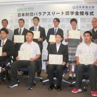 Nippon Foundation chairman Yohei Sasagawa (far left, second row) and eight Paralympic athletes who will receive scholarships from the foundation pose for photos at a ceremony at Nippon Sport Science University in Tokyo on Tuesday. | KAZ NAGATSUKA