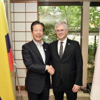 Colombian Ambassador Gabriel Duque (right) shakes hands with Komeito chief Natsuo Yamaguchi during a reception to celebrate the 110th anniversary of the establishment of diplomatic relations between Colombia and Japan at the official residence of Colombia on May 25. | YOSHIAKI MIURA