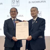 Nomura Co. President and CEO Shuji Enomoto (left) and former Prime Minister Yoshiro Mori hold a certificate of agreement at a ceremony announcing that the facilities and event managing company has agreed to become an official supporter of the 2020 Tokyo Olympics and Paralympics in Tokyo on June 4. | AYUMI KIMURA