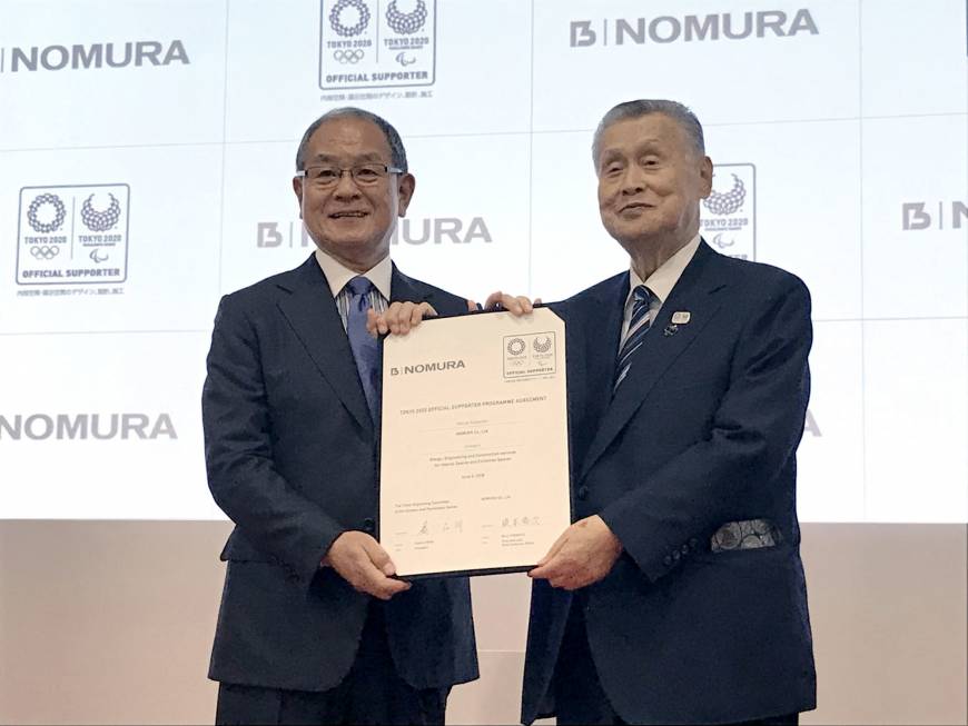 Nomura Co. President and CEO Shuji Enomoto (left) and former Prime Minister Yoshiro Mori hold a certificate of agreement at a ceremony announcing that the facilities and event managing company has agreed to become an official supporter of the 2020 Tokyo Olympics and Paralympics in Tokyo on June 4.