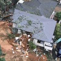 Rescuers try to local residents trapped in a mudslide on Saturday morning in Kitakyushu, Fukuoka Prefecture. | KYODO