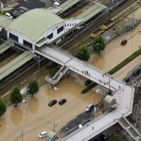 The main road in front of JR Saka Station of Saka, Hiroshima Prefecture, is flooded with muddy water Saturday after heavy rains hit a wide portion of western Japan Friday. NHK reported at least three mudslides were triggered by the heavy rain in the town, leaving two residents missing. | KYODO