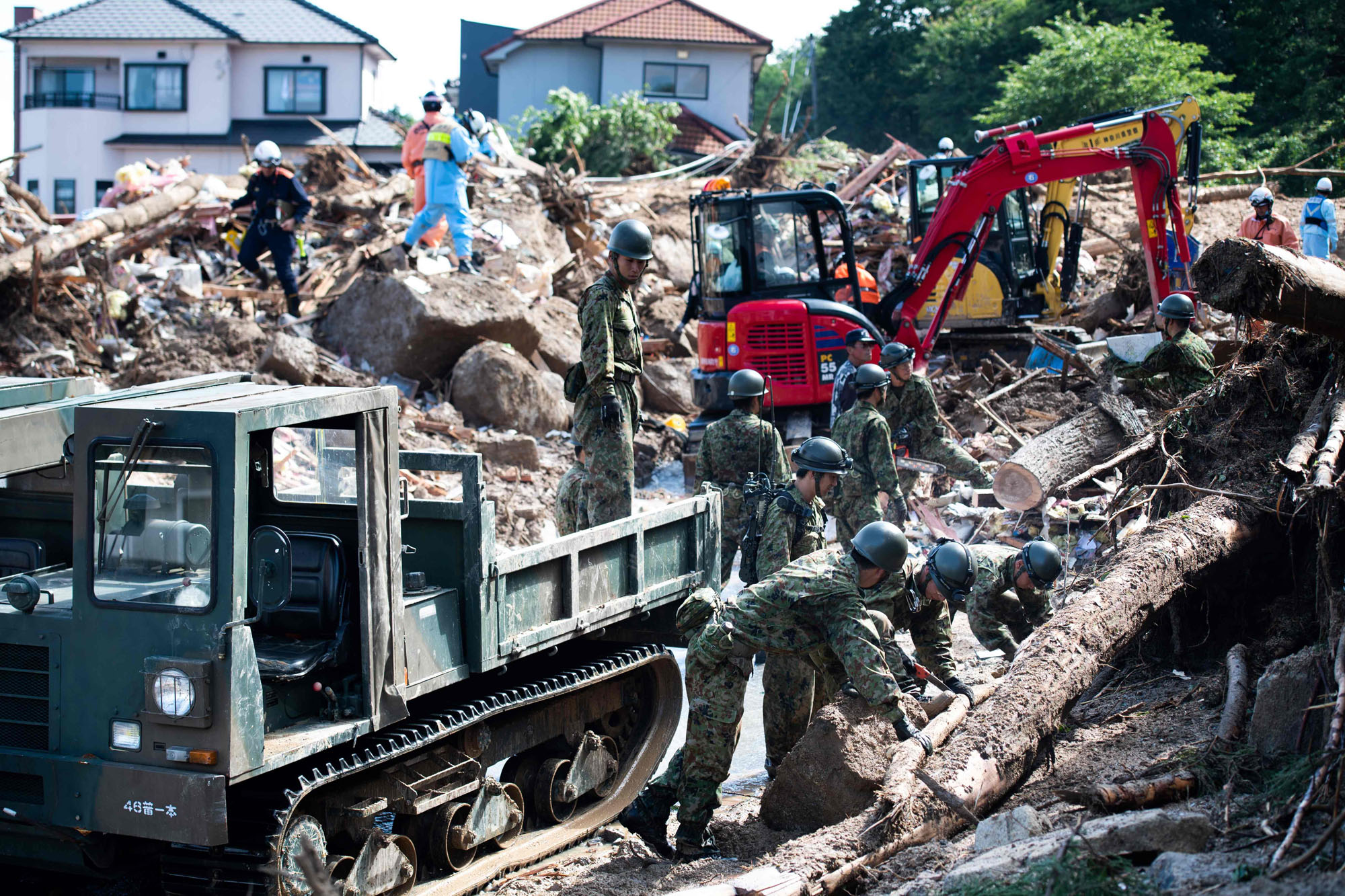 Rescue workers and soldiers clear debris from a street in a flood-hit area in Kumano, Hiroshima Prefecture, on Monday. Torrential rain across western Japan has forced some automakers and other companies to suspend operations. | AFP-JIJI