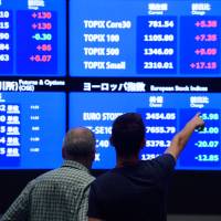 People look at stock price screens at the Tokyo Stock Exchange last week. Speculation is high that the Bank of Japan may change how it buys shares. | BLOOMBERG