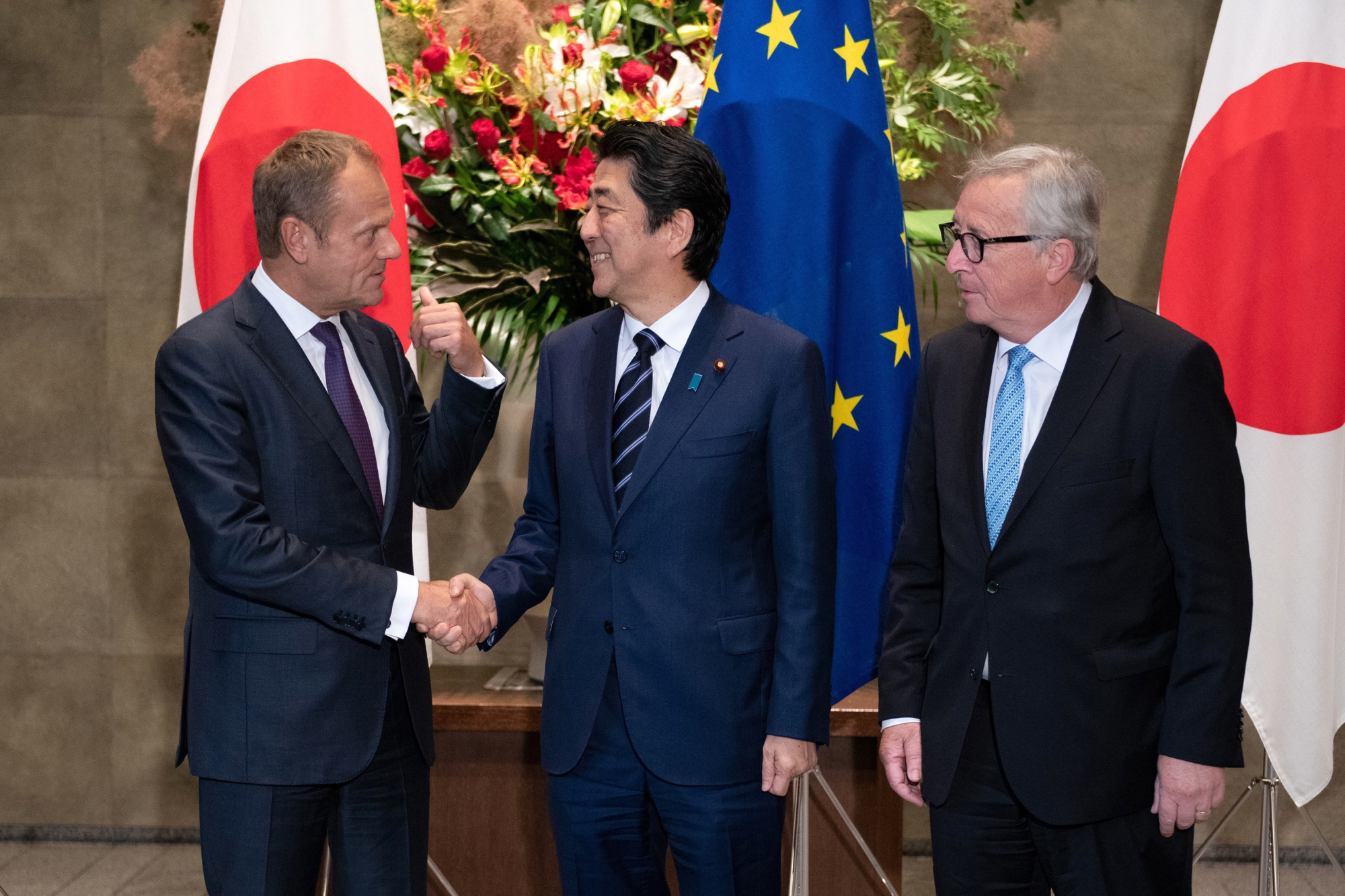 Prime Minister Shinzo Abe shakes hands with European Council President Donald Tusk as European Commission President Jean-Claude Juncker looks on before signing a free trade pact in Tokyo on Tuesday. | AP