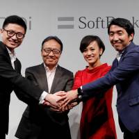 DiDi Chuxing Vice President Stephen Zhu (left), SoftBank Corp. CEO Ken Miyauchi (second from left), DiDi Chuxing President Jean Liu (second from right), and SoftBank Corp. executive Keigo Sugano (right) pose after a news conference about their Japanese taxi-hailing venture in Tokyo on Thursday. | REUTERS