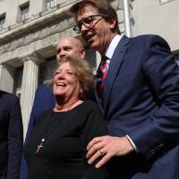 Plaintiff Gail Ingham (front) stands outside the civil courthouse with attorneys (from left) Lee Cirsch, Eric Holland and Mark Lanier following a verdict against health care giant Johnson &amp; Johnson on Thursday in St. Louis. | CHRISTIAN GOODEN/ST. LOUIS POST-DISPATCH / VIA AP