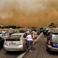 The National Road in Kineta, near Athens, is blocked by a wildfire on Monday. | AFP-JIJI