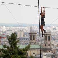 Tatian-Mosio Bongonga hangs from a tightrope as she pauses while scaling the Monmartre hill in Paris on Saturday. | REUTERS