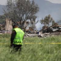 A police officer guards the perimeter around the wreckage of several fireworks workshops in Tultepec, Mexico, Thursday. More than a dozen people were killed and at least 40 injured when a series of explosions ripped through fireworks workshops in the town just north of Mexico City. | AP