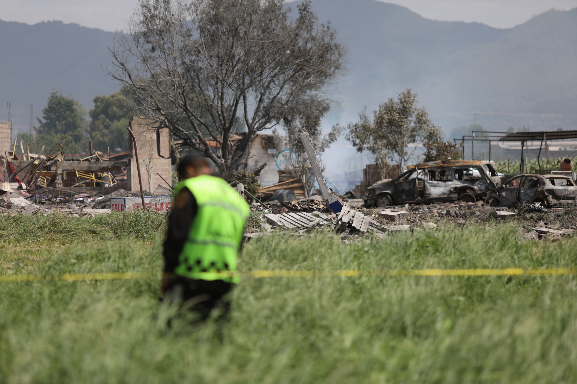 A police officer guards the perimeter around the wreckage of several fireworks workshops in Tultepec, Mexico, Thursday. More than a dozen people were killed and at least 40 injured when a series of explosions ripped through fireworks workshops in the town just north of Mexico City. | AP