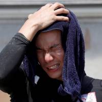A volunteer helping recovery efforts wipes away sweat as he takes a break during a heat wave at a flood-affected area of Kurashiki, Okayama Prefecture, on Saturday. | REUTERS