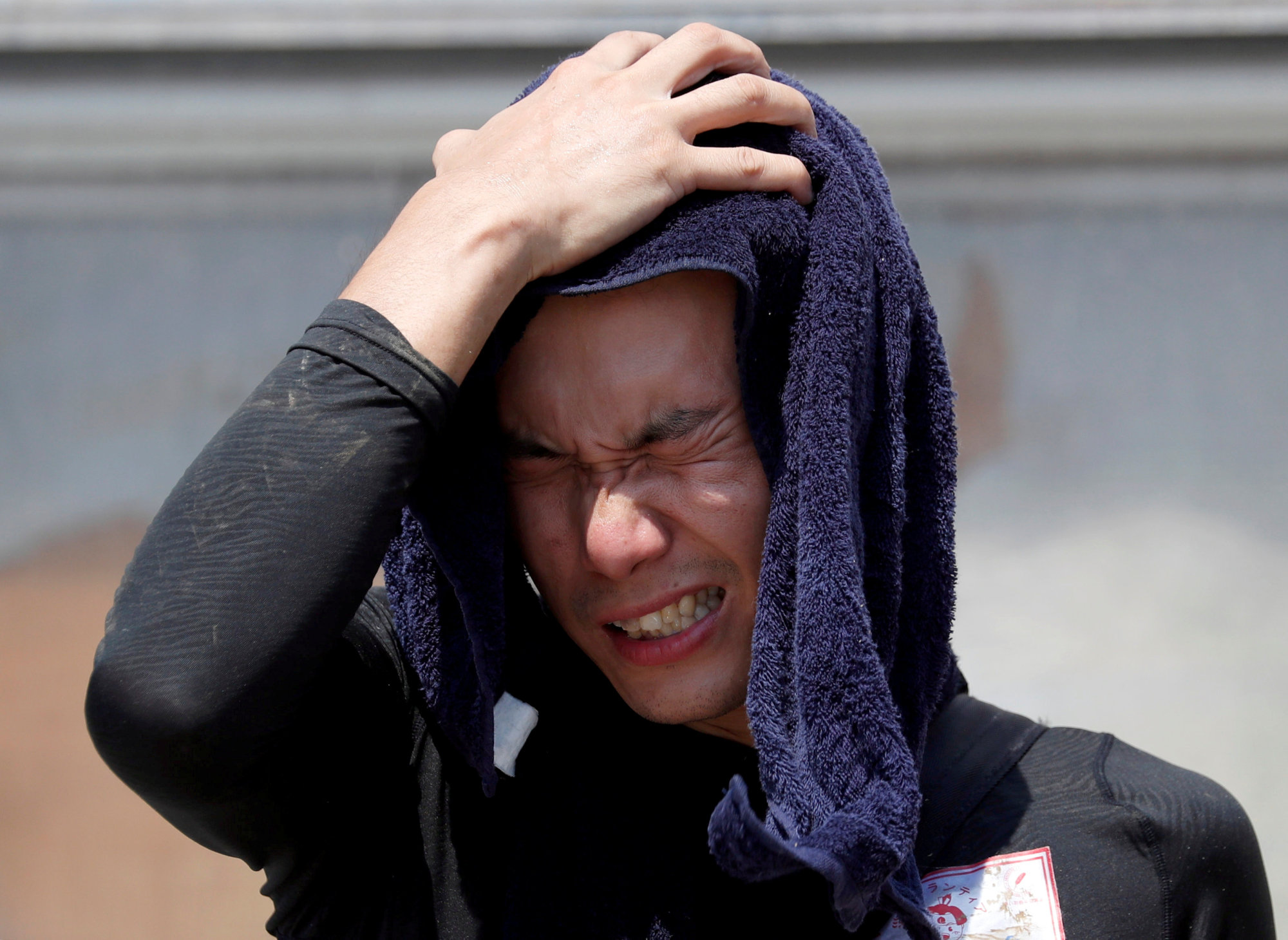 A volunteer helping recovery efforts wipes away sweat as he takes a break during a heat wave at a flood-affected area of Kurashiki, Okayama Prefecture, on Saturday. | REUTERS
