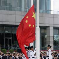 Hong Kong\'s guard of honor hoists a Chinese flag during a ceremony to mark the 21st anniversary of the Hong Kong handover to China in the city Sunday. | AP