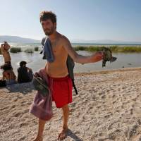 An Israeli man holds rubble as Israeli forces search the Sea of Galilee coast for the remains of a reported drone launched from Syria and intercepted by a Patriot missile on Wednesday near the Ha-On kibbutz, northeastern Israel. Israel intercepted the drone launched from Syria with a Patriot missile on Wednesday, setting off sirens in the occupied Golan Heights, the army said. | AFP-JIJI
