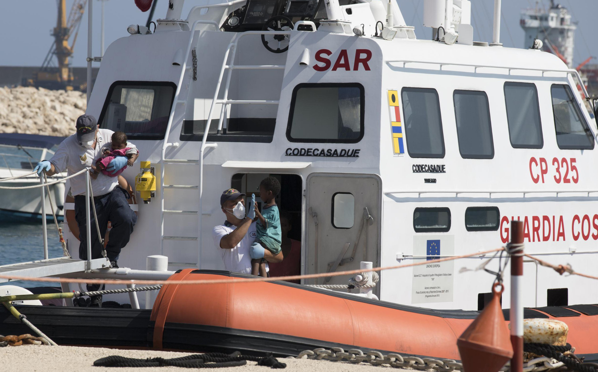 Children disembark from an Italian Coast Guard ship in the port of Pozzallo, Southern Italy, Sunday. Another day's worth of food and beverages was sent Sunday to a pair of military ships off Sicily as Italy waited for more European nations to pledge to take a share of the hundreds of migrants on board before allowing the asylum-seekers to step off onto Italian soil. | FRANCESCO RUTA / ANSA / VIA AP