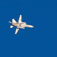 A picture taken Thursday near the Ein Zivan settlement in the Israeli-annexed Golan Heights, shows a Syrian MiG-23 flying above buildings across the border in Syria during airstrikes backing a Syrian-government-led offensive in the southern province of Quneitra. | AFP-JIJI