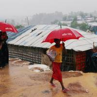 Rohingya refugees walk in the Kutupalong camp during heavy rain in Cox\'s Bazar, Bangladesh, Wednesday. | REUTERS