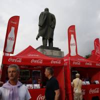 Booths marketing products by event sponsors Budweiser and Coca-Cola stand beside a statue of Lenin on Wednesday, as fans arrive for the semifinal match between Croatia and England at Luzhniki Stadium during the 2018 soccer World Cup in Moscow. | AP