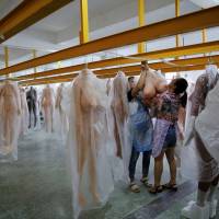 Workers hang a sex doll in the warehouse at the WMDOLL factory in Zhongshan, Guangdong Province, China, on July 11. | REUTERS