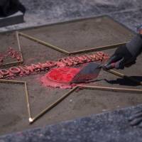 Workers replace the star of U..S President Donald J. Trump on the Hollywood Walk of Fame after it was destroyed by a vandal in the early morning hours on Wednesday in Los Angeles. | AFP-JIJI