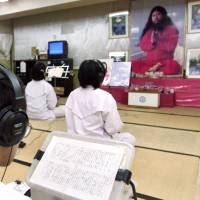 Followers of doomsday cult Aum Shinrikyo chant before a portrait of guru Shoko Asahara during religious training at Aum\'s Adachi Ward office in Tokyo in July 1999. | REUTERS