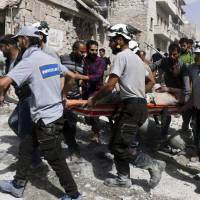 White Helmet rescue workers move a victim after airstrikes in Syria in September 2016. | SYRIAN CIVIL DEFENSE WHITE HELMETS / VIA AP