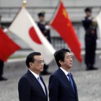 Chinese Premier Li Keqiang and Prime Minister Shinzo Abe observe an honor guard in Tokyo on May 9. | BLOOMBERG
