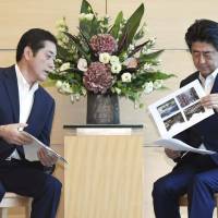 Ehime Gov. Tokihiro Nakamura briefs Prime Minister Shinzo Abe in Tokyo on damage caused by the floods and landslides triggered by recent heavy rain in western Japan. | KYODO