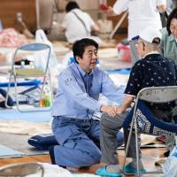 Prime Minister Shinzo Abe visits a shelter for people affected by the recent flooding in the Mabicho district of Kurashiki, Okayama Prefecture, on Wednesday. | AFP-JIJI