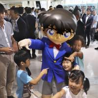 Children play with a mascot from the long-running comic book and anime series \"Detective Conan\" at the revamped Tottori Sand Dunes Conan Airport in Tottori Prefecture on Saturday. | KYODO