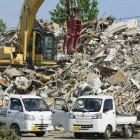 Trash and debris is seen piled up at a makeshift garbage disposal site in the Mabicho district in Kurashiki, Okayama Prefecture, on Sunday. | KYODO