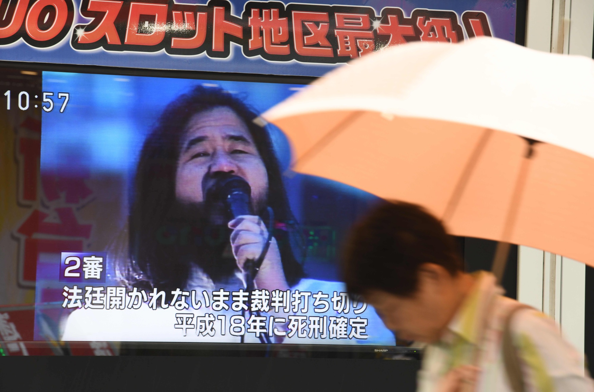 A pedestrian walks past a screen flashing news about the execution of Shoko Asahara, founder of the Aum Shinrikyo doomsday cult, in Tokyo on Friday. | AFP-JIJI