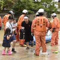 Rescuers help local residents to evacuate Saturday in the town of Saka, Hiroshima Prefecture. | KYODO