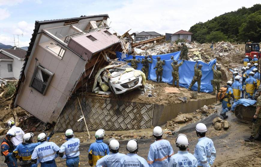 Rescue workers hunt for missing people at the scene of a home destroyed in a mudslide triggered by torrential rains in the town of Kumano, Hiroshima Prefecture, on Monday morning.