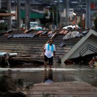 A local resident walks in front of submerged and destroyed houses in a flooded area of Kurashiki, Okayama Prefecture, , on Sunday | REUTERS