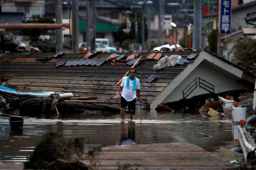 A local resident walks in front of submerged and destroyed houses in a flooded area of Kurashiki, Okayama Prefecture, , on Sunday