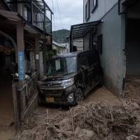 A car is seen trapped in the mud after floods in Saka, Hiroshima Prefecture, on Sunday. | AFP-JIJI