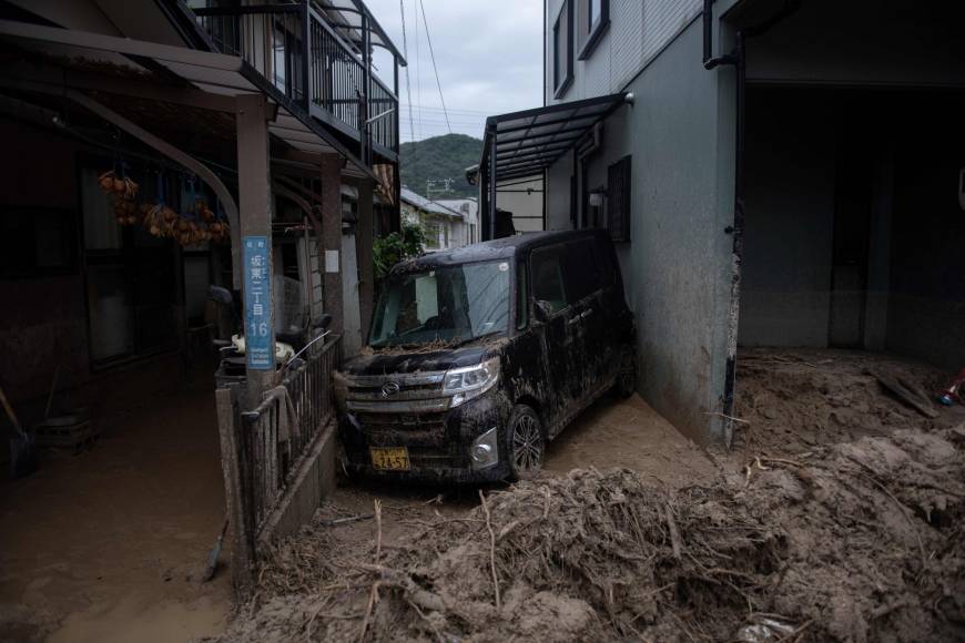A car is seen trapped in the mud after floods in Saka, Hiroshima Prefecture, on Sunday.