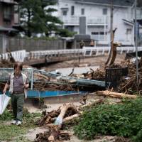 A man walks past a street in Saka, Hiroshima Prefecture, on Sunday after the area was devastated by floods. | AFP-JIJI