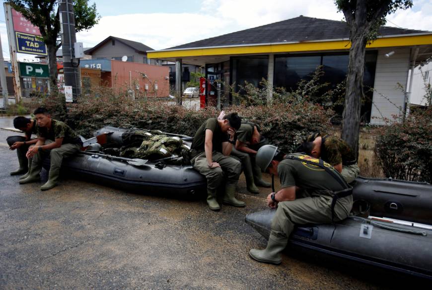Rescue workers rest in an area of Kurashiki, Okayama Prefecture, on Sunday after heavy rains inundated western Japan.
