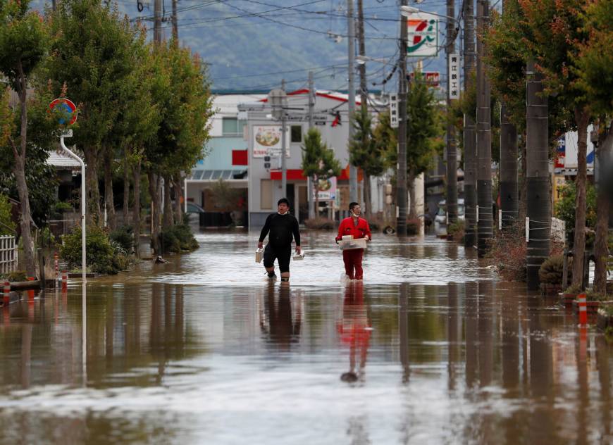 Men make their way in a flooded area of Kurashiki, Okayama Prefecture, on Sunday.