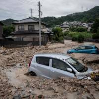 Cars are seen trapped in the mud after floods in Saka, Hiroshima Prefecture, on Sunday. | AFP-JIJI