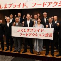 Fukushima Gov. Masao Uchibori (center), Olympic medalist Yuko Arimori (third from right) and others pose on June 20 in the city of Fukushima to announce plans to expand sales channels for Fukushima-made produce. | FUKUSHIMA MINPO