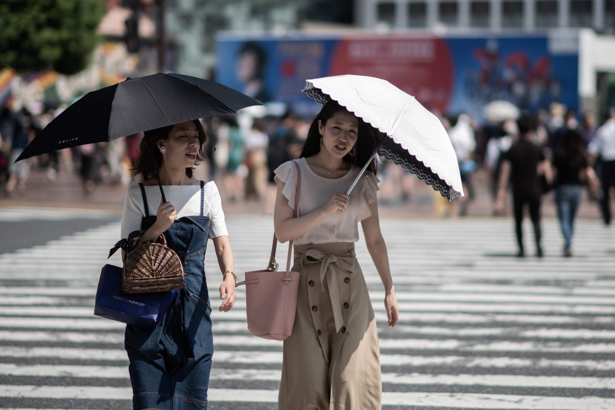 Women shield themselves from the sun with umbrellas in Tokyo on Tuesday as Japan suffers from a heat wave. | AFP-JIJI