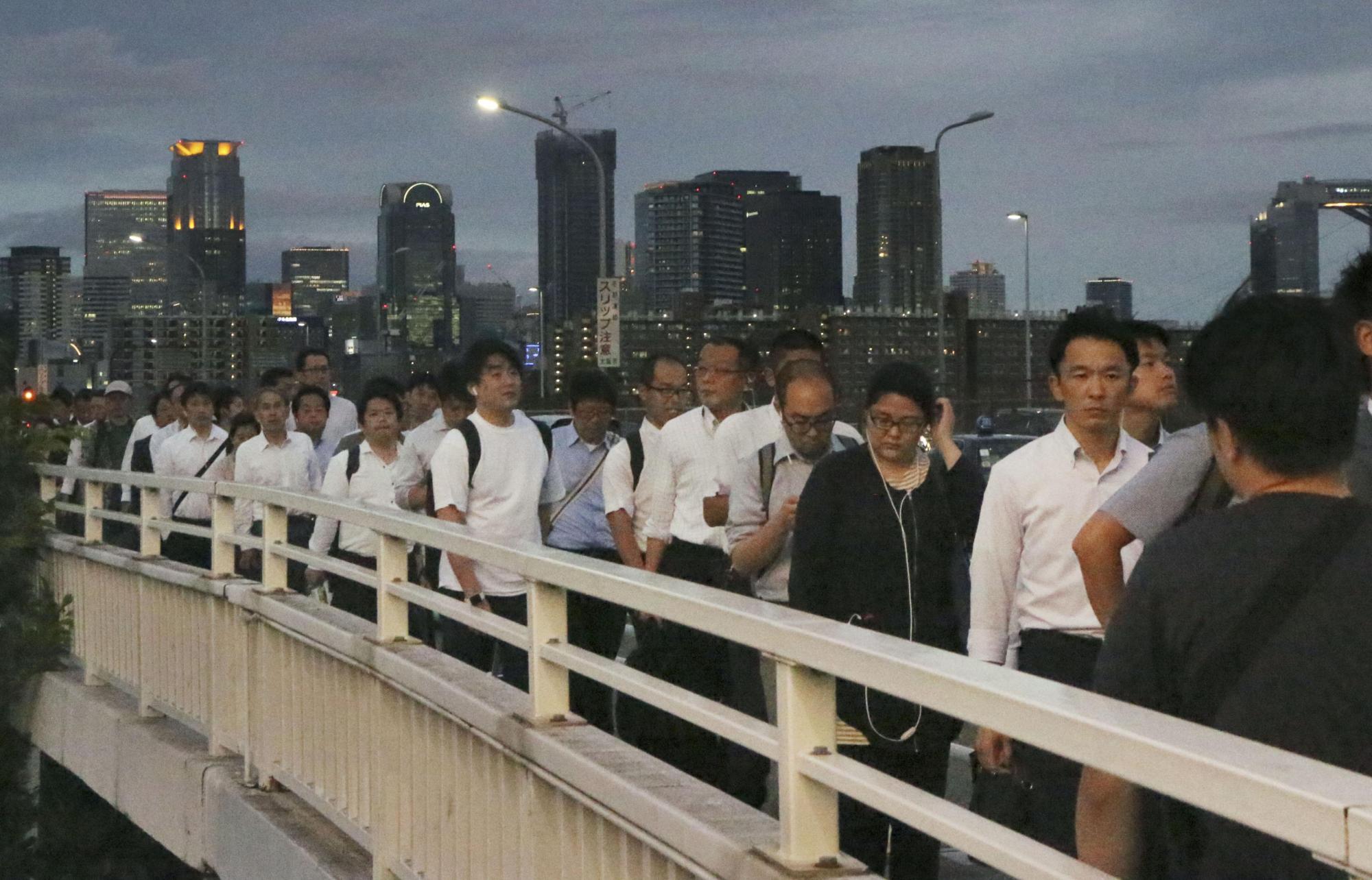 Pedestrians crowd the Shin-Yodogawa Bridge in Osaka on the evening of June 18 after public transportation services were disrupted by the major earthquake that hit the region earlier in the day. | KYODO