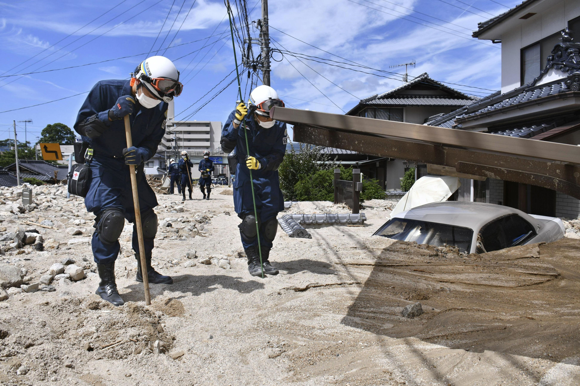 Rescuers search for missing people near houses and cars buried in mud in Kure, Hiroshima Prefecture, on Wednesday. | KYODO