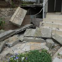 A collapsed concrete wall litters the ground in front of a house in Takatsuki, Osaka Prefecture, after a magnitude 6.1 struck on June 18. Tens of thousands of masonry walls that don\'t meet current building standards remain in place across the nation. | BLOOMBERG