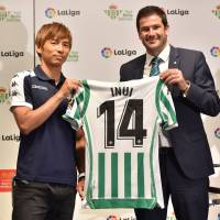 Takashi Inui (left) and Real Betis director and general manager of business Ramon Alarcon display a uniform with the No. 14 during a news conference to announce Inui\'s signing with the club on Thursday. | AFP-JIJI